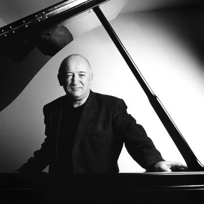 Black and white photo of John O'Conor standing behind a piano